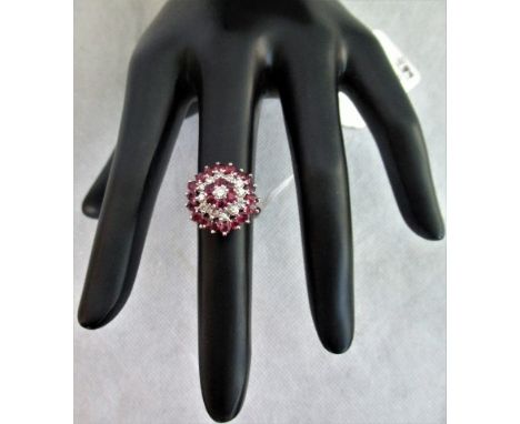 A ruby and diamond cluster ring, the single central diamond encircled by three individual stone set bands on stilted open sho