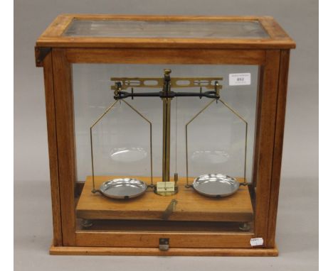 A set of scientific scales in wooden and glass case. The case 46 cm wide.
