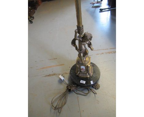 Brass standard lamp with cherub support, inset with porcelain panels 