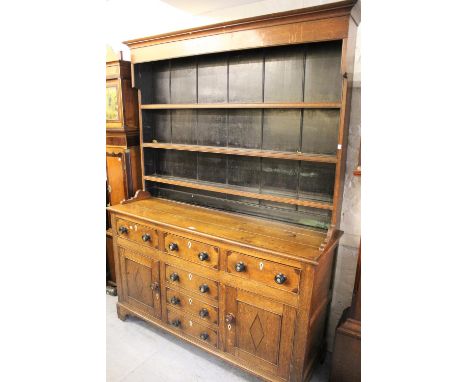 Early 19th Century oak dresser, the boarded shelf back above an arrangement of drawers and cupboard doors on bracket feet, 63