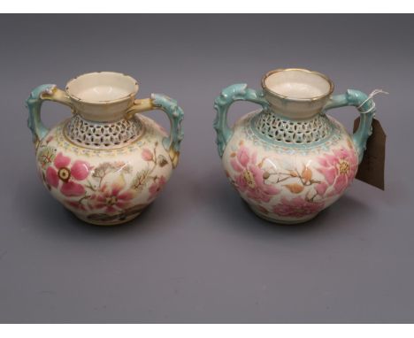 Near pair of Zsolnay Pecs squat baluster form two handled vases decorated with flowers on a cream ground beneath reticulated 