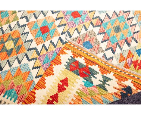An Anatolian Turkish Kelim, the field with serrated lozenge medallions in multiple bright colours, enclosed by a twin arrow h