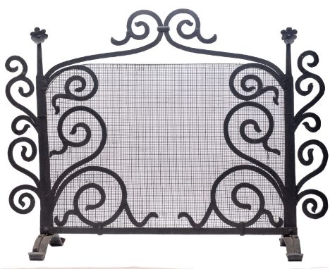 A wrought iron and mesh firescreen in Arts & Crafts style, 20th century; with shallow arched openwork scrolling cresting and 
