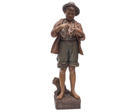 A Friedrich Goldscheider pottery figure, of a young barefoot boy in jacket, shorts and hat, striking matches, on a rustic squ