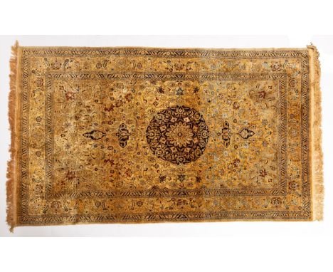 A Kashmir silk rug, the light brown field with a central circular indigo pole medallion, all over palmette and scrolling flor