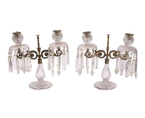 A pair of Regency cut glass and ormolu mounted twin light table lustres, early 19th century; with foliate cast metal drip pan
