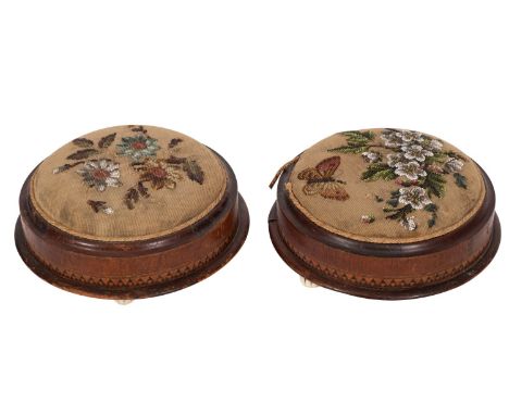 A pair of Victorian walnut and inlaid circular footstools; with beadwork and needlework tops in a design with butterfly and s
