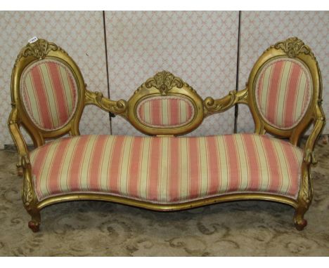 A small dolls size sofa with alternating striped upholstered serpentine shaped seat and cameo shaped padded back within a gil