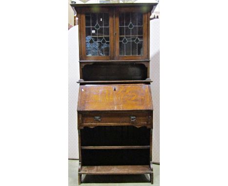 An Edwardian Art Nouveau/Crafts style slim oak bureau bookcase, the upper section enclosed by a pair of leaded light panelled
