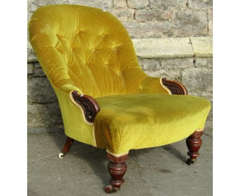 A Victorian spoon and button back drawing room chair with upholstered finish and partial carved showwood frame raised on turn