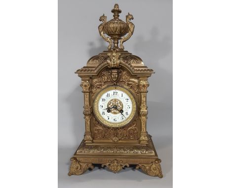 A substantial Victorian mantel clock in a cast brass case detailing mask, scroll and repeating geometric detail enclosing an 