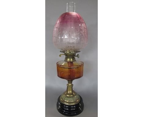 A Duplex oil lamp with a brass stand and an orange faceted font and a fading cranberry shade, 57 cm high 