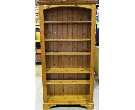 A modern stripped pine freestanding open bookcase with two fixed and two adjustable shelves with moulded detail and raised on