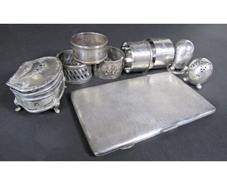 A silver engine turned cigarette case, 4 silver napkin rings, trinket box, two pepper pots, an Indian silver metal napkin rin