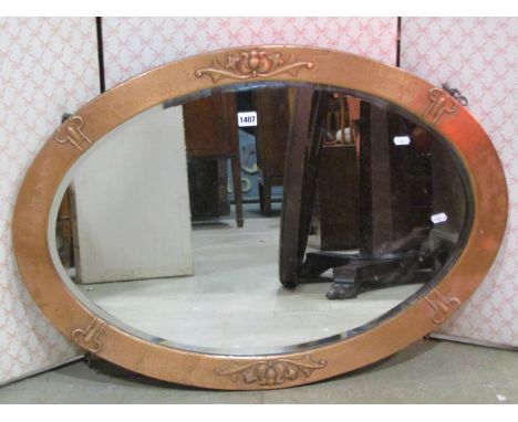 An arts and crafts style oval wall mirror with bevelled edge plate, within a copper clad and embossed frame, 86cm x 62cm, tog