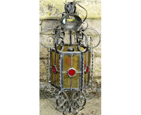 A hanging porch/hall lantern of hexagonal form with textured coloured glass panels within a scrolling iron work frame, 70 cm 