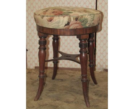 A Regency mahogany piano/music stool with circular upholstered seat raised on ring turned, tapered and slightly splayed suppo