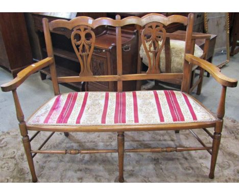 An Edwardian lightweight two seat sofa with stained beechwood frame, pierced vase shaped splats, upholstered pad seat and tur