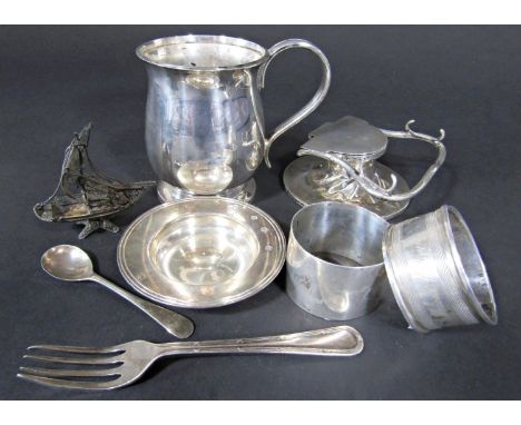 A collection of silverware including a tankard, inkwell, two napkin rings, mustard spoon, fork and a small dish, 12 ozs all i