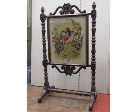 A mid 19th century mahogany framed firescreen, the turned and carved framework with simulated rosewood finish, enclosing a ne
