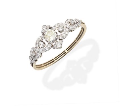 DIAMOND BANGLE, CIRCA 1890The front centrally-set with a cushion-shaped diamond of yellow tint, within a scrolling openwork s