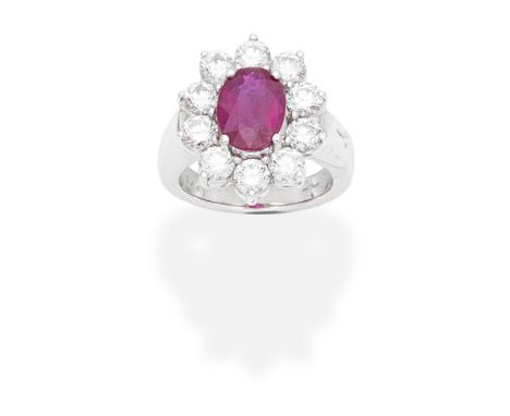 RUBY AND DIAMOND CLUSTER RINGThe oval-cut ruby, weighing 3.02 carats, within a brilliant-cut diamond surround, mounted in 18 