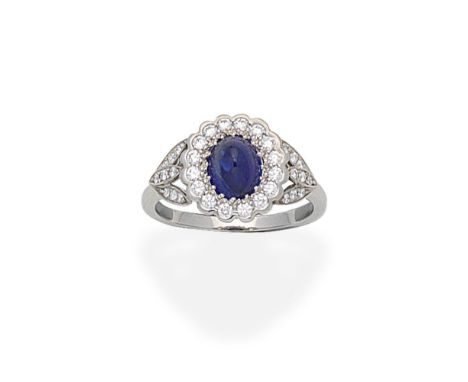 SAPPHIRE CLUSTER RINGThe cabochon sapphire within a brilliant-cut diamond surround, between trifurcated shoulders set with si