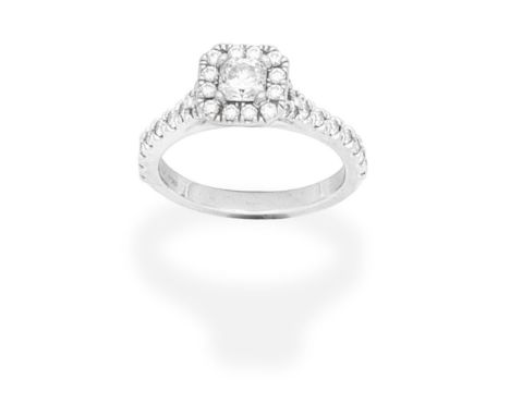 DIAMOND CLUSTER RINGThe square-cut diamond within a brilliant-cut diamond surround, between brilliant-cut diamond shoulders, 
