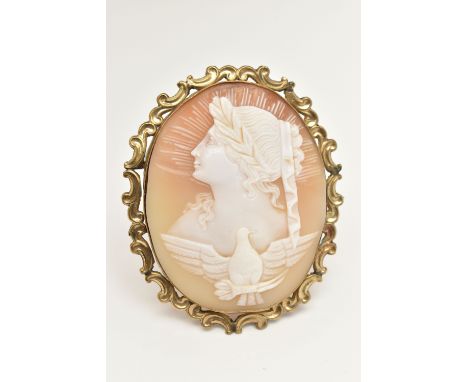 A LARGE YELLOW METAL CAMEO BROOCH, carved shell cameo depicting a lady in profile with sun burst atop of a bird with open win