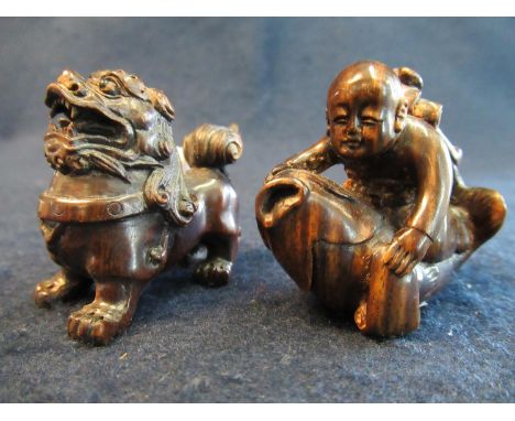 Two Japanese carved hardwood netsukes, one of a Shishi Buddist lion. The other the legendary child Kintaro with an axe on his