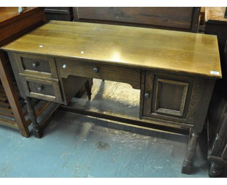 Mid Century oak knee hole desk having an arrangement of three drawers, one cupboard, standing on baluster turned legs. (B.P. 