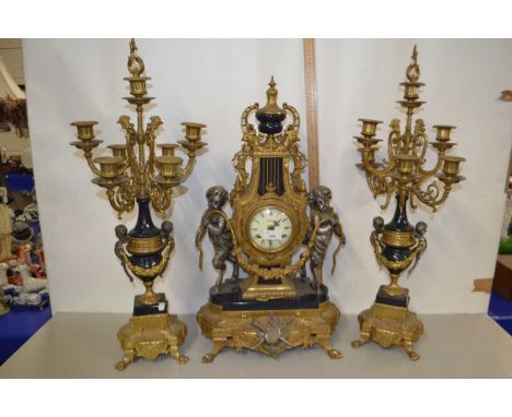20th Century French clock garniture with central clock with cherub decoration together with a pair of seven light candelabra