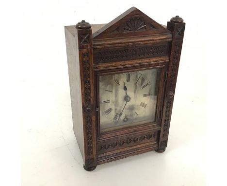 A 1920s oak mantel clock with carved architectural style facade, on bun feet, stamped John FB Donaldson, Edinburgh to interio