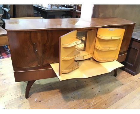 A Beautility mid century low cocktail cabinet, the central door opening to an expanding bar with shelves and workspace, flank