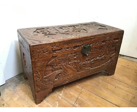 A Chinese camphorwood chest, carved with typical Chinese scenes to all sides, unfitted interior, on bracket feet (51cm x 89cm