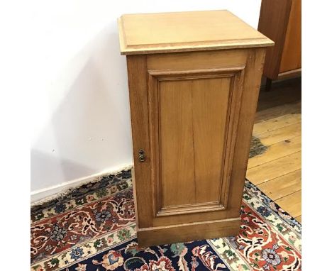 A Victorian pine bedside cabinet with panelled door, fitted single shelf to interior, on plinth base (75cm x 36cm x 40cm)