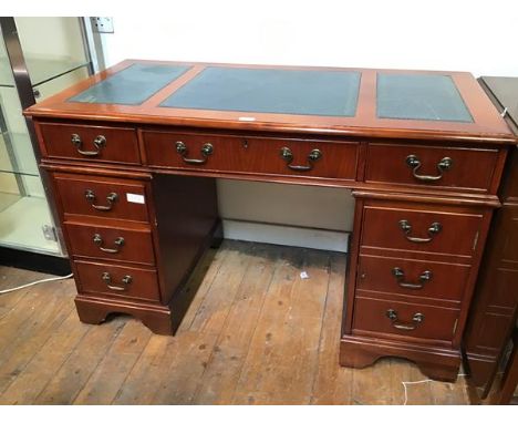 A reproduction cherrywood pedestal desk with tooled leather top, fitted one long and two short frieze drawers, one pedestal f