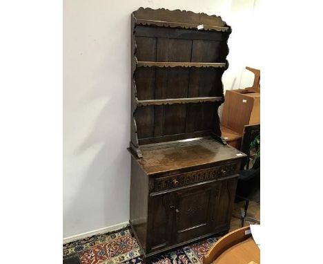 A 1920s oak dresser with plate rack above a carved base fitted single frieze drawer and single panel door to base, on bracket