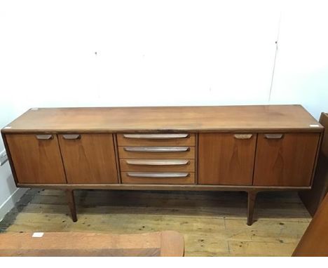 A mid century teak sideboard, with a pair of two door single shelf cupboards, flanking four drawers, on turned tapering suppo