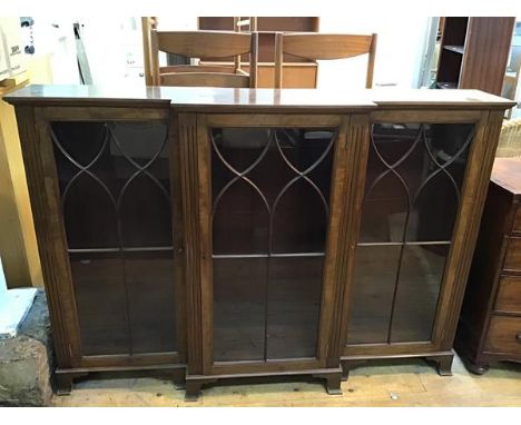 12A reproduction mahogany breakfront bookcase with three glazed doors with fluted pilasters, on bracket feet, lacking shelves