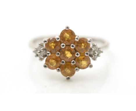 A golden topaz and diamond ring, the seven topaz in cluster mount flanked by diamond shoulders, on 9ct white gold shank, ring