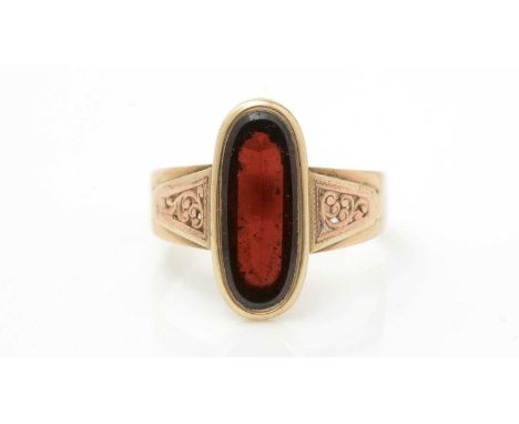A garnet ring, the oval garnet flanked by scrolling shoulders, in gold mount and shank, tests as approximately 14ct, ring siz