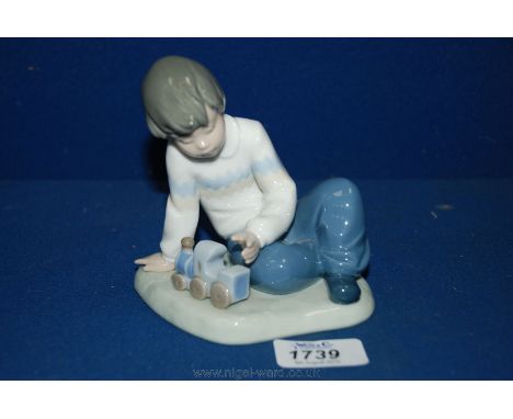 A Nao figure of a boy playing with a train.