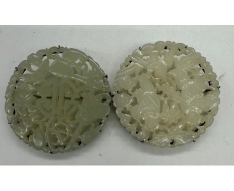 A pair of Chinese jade brooches, differing designs on white metal settings 55mm diameter