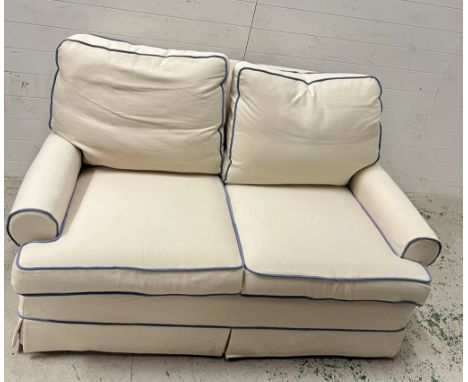 A cream two seater sofa with blue piping and loose covers (H88cm W160cm D92cm)