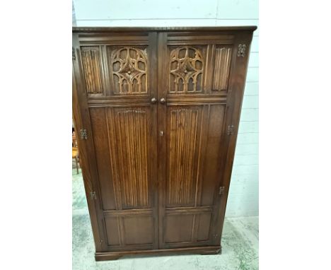 An oak Art and Craft double wardrobe carving to front (W122cm D51cm H185cm)