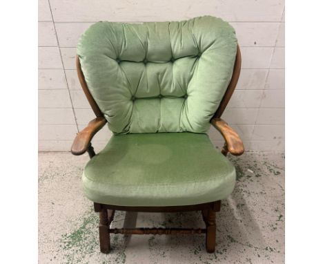 A Mid Century stained teak Ercol style arm chair upholstered in a pale green fabric