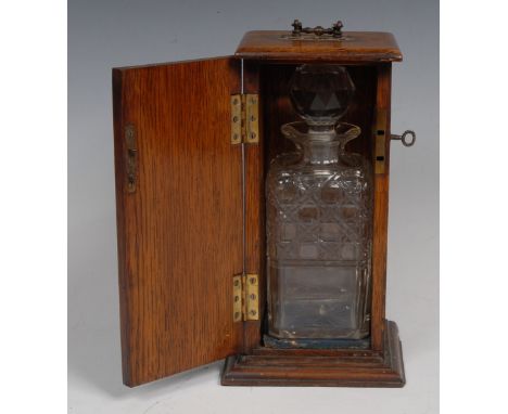 A late Victorian oak single decanter box, oversailing top with brass carrying handle above a door carved with leaves and cent