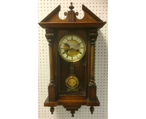 A walnut wall clock, architectural pediment, brass dial, enamelled chapter ring, Roman numerals. 