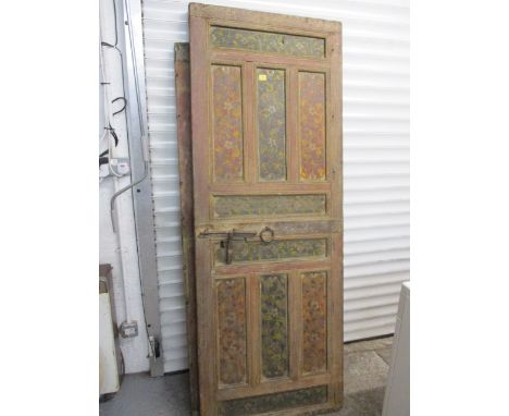 A continental soft wood painted and panelled door, decorated with flora with a central bolt and ring handle, 75 x 28